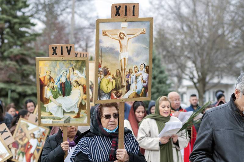 Parishioners follow behind displaying placards with illustrations of the individual stations on Friday in Sterling.