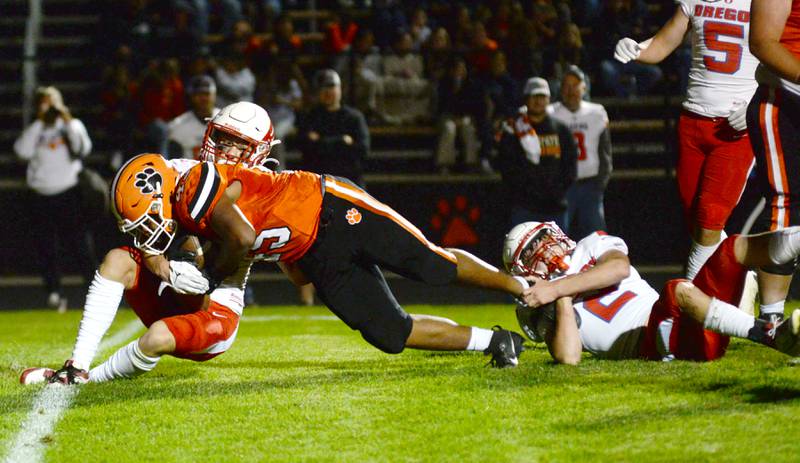 Byron's Kaden McGough (45) stretches for the end zone as Oregon's Cooper Johnson (2) hangs on to his foot and Ethan Mowry (3) grabs his shoulder pads during a Friday, Sept. 27, 2024 game in Byron. The Tigers remained undefeated with a 49-7 win over the Hawks.