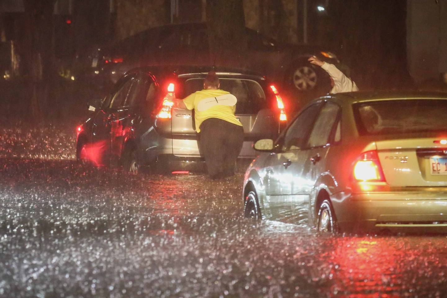 People push a stuck car on McHenry Avenue in Crystal Lake during Friday night storms.