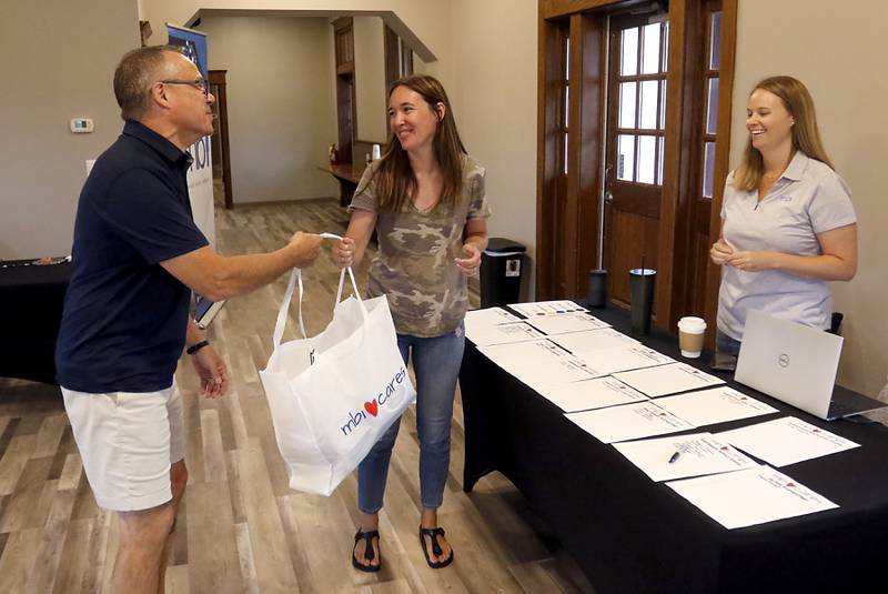 Kevin Newton, left and Katie Homuth, right both of MBI, talks with Northwood Middle School teacher, Erika Liuzzi as Newton hands her a bag of school supplies Monday, August 8, 2022, at the Woodstock Metro Station. MBI, Woodstock-based company, purchased classroom supplies for teachers in all District 200 and Woodstock parochial schools through the company's MBI Cares program.