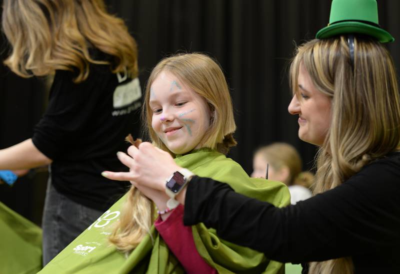 Forest Road 4th grader Lily Ward gets handed her pony tails by D'Amici hair stylists Taylor Popovich during the St. Baldrick fundraiser held Thursday, March 7, 2024.