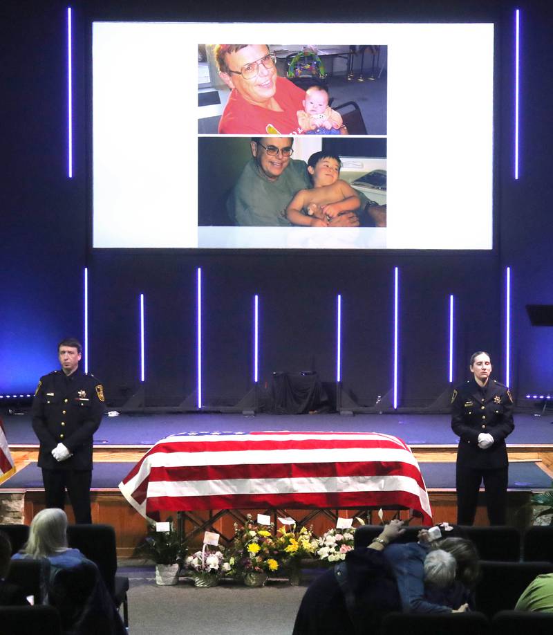 DeKalb County sheriff's deputies stand on either side of the casket of former DeKalb County Sheriff Roger Scott as a slide show plays on the screen above during his visitation Thursday, March 6, 2025, at Bethany Road Bible Church in DeKalb. Scott, who was the county sheriff for more than 30 years, died on February 23 at the age of 78.