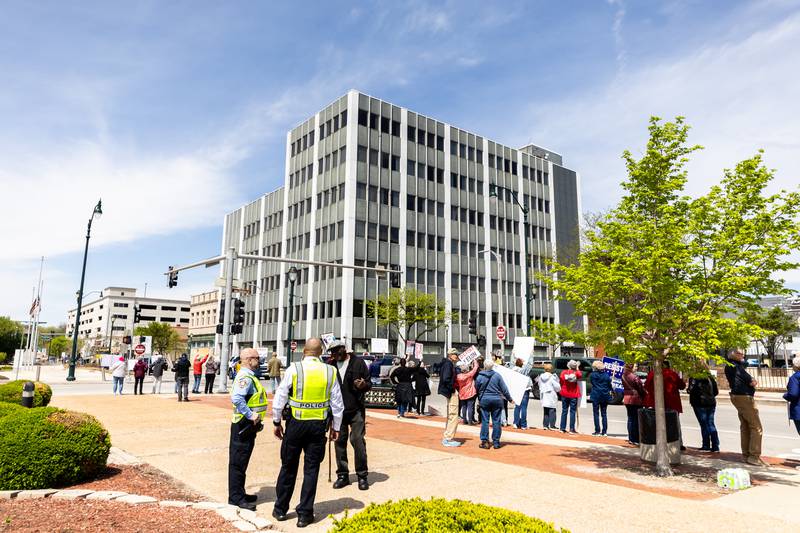 Joliet Police officers chat with a participate as the May Day Weekend Rally unfold on Jefferson Street in Downtown Joliet on May 3, 2025.