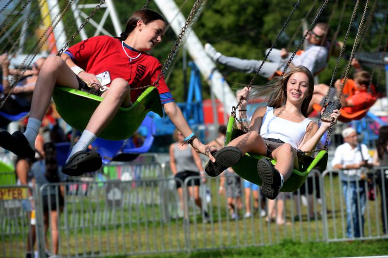 Fourteen-year-olds Skye Ballard, (left) and Hope Lance, both of Dixon, ride the swings at the carnival at the Ogle County  Fair on Friday, Aug. 2, 2024, west of Oregon.