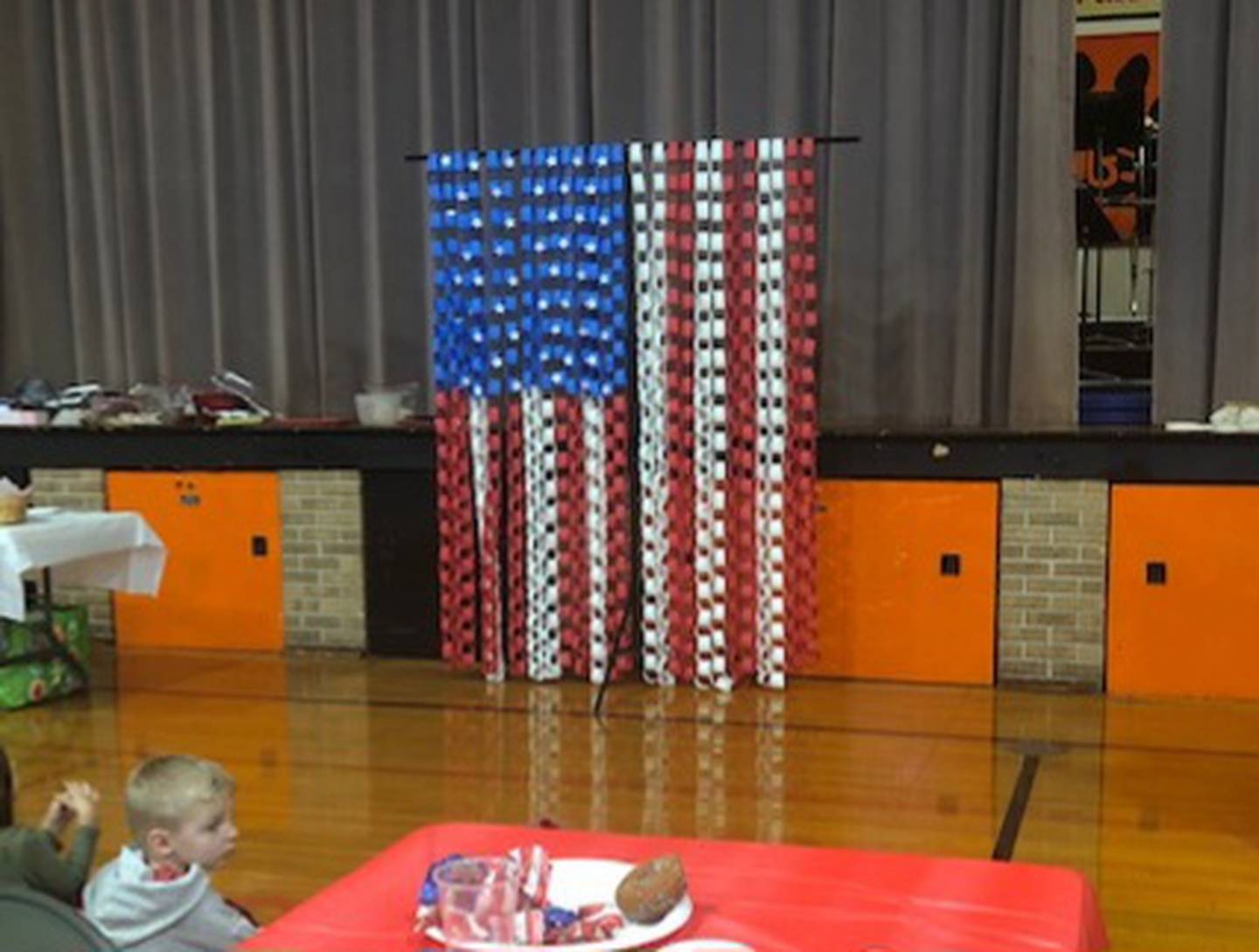 Family photos of NGS students with their Veteran family members, with a backdrop of a paper prepared American Flag was on display.
