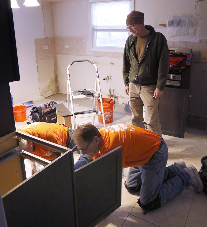 Veteran Craig Taylor watches as Tom Powers and Jerry Webb, from Home Depot, install new cabinets in Taylor's home on Thursday Jan. 16, 2025. The kitchen remodel for Taylor is part of the 30 Days for 30 Vets program.