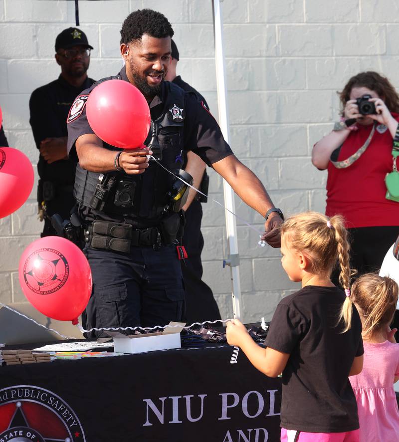 Northern Illinois University Police officers hand out balloons Tuesday, Aug. 5, 2025, at their booth during National Night Out in the Hy-Vee parking lot in Sycamore.