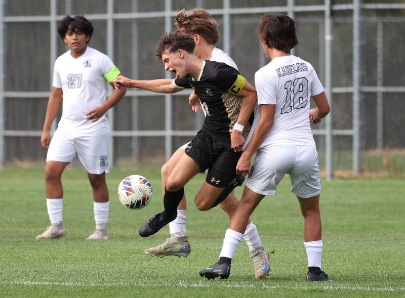 Sycamore's Noah Daykin is triped up trying to get between two Kaneland defenders during their game Monday, Oct. 6, 2025, at Sycamore High School.