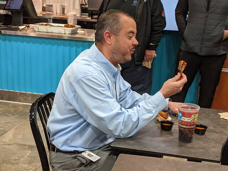 Oswego Village Administrator Dan Di Santo gets ready to bite into a wing at Woodie's Wings. The Oswego Area Chamber of Commerce hosted a ribbon-cutting ceremony for Gas N Wash, Scooter’s Coffee and Woodie’s Wings on Nov. 14, 2025.