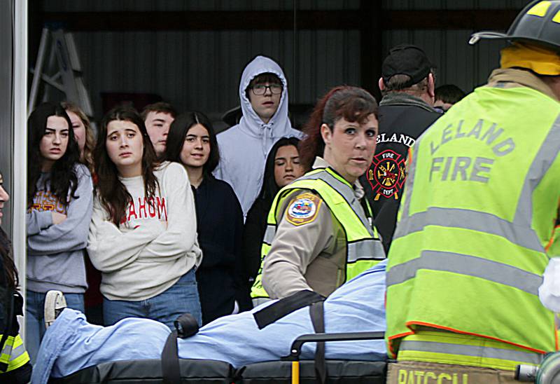 Leland High School students (from left) Julia Winckler, Carol Pegoraro, and Naroa Iturrioz watch their classmate Jessica Barry be transported to a ambulance with La Salle County Sheriff deputy Felecia Rasmussen, La Salle County Deputy Sheriff during a Mock Prom drill at Leland High School on Friday, May 6, 2022 in Leland.