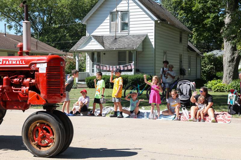 Children wave to the driver of an antique tractor during the 104th annual Herscher Labor Day Celebration Grand Parade on Monday, Sept. 1, 2025.