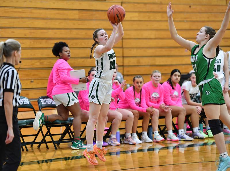 Glenbard West's Julia Benjamin (10) shoots for three points as York's Amelie Van Heukelum ((right) defends during a game on Jan. 22, 2024 at Glenbard West High School in Glen Ellyn.