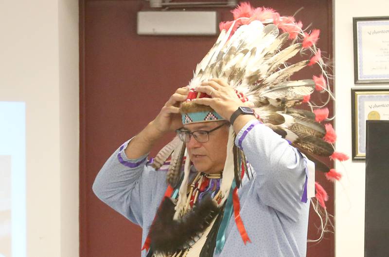 Gerald Savage, a tribal elder with the Ho-Chunk Nation, places his bonnet on his head during a program on Monday, Aug. 4, at the Richard A. Mautino Memorial Library in Spring Valley. Chief Savage spoke to about 40 people about the history of the Ho-Chunk Tribe, Native American instruments, stories and more. Chief Savage is an Illinois Humanities Road Scholar who speaks across the State and Wisconsin.