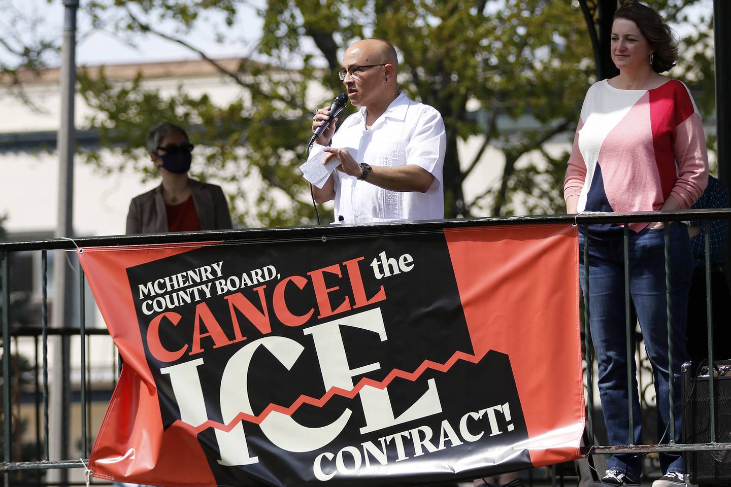 McHenry County board members Carlos Acosta, center, and Kelli Wegener, right, speak to a crowd of approximately 80 attendees at a rally to end McHenry County's contract with U.S. Immigration and Customs Enforcement on Saturday, May 1, 2021 in Woodstock.