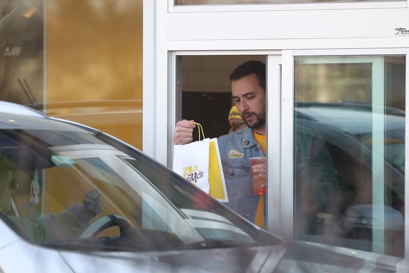 An employee hands an order to a customer at CosMc’s, McDonald’s first small format beverage driven concept drive-thru restaurant, on Friday, Dec. 8, 2023, in Bolingbrook.