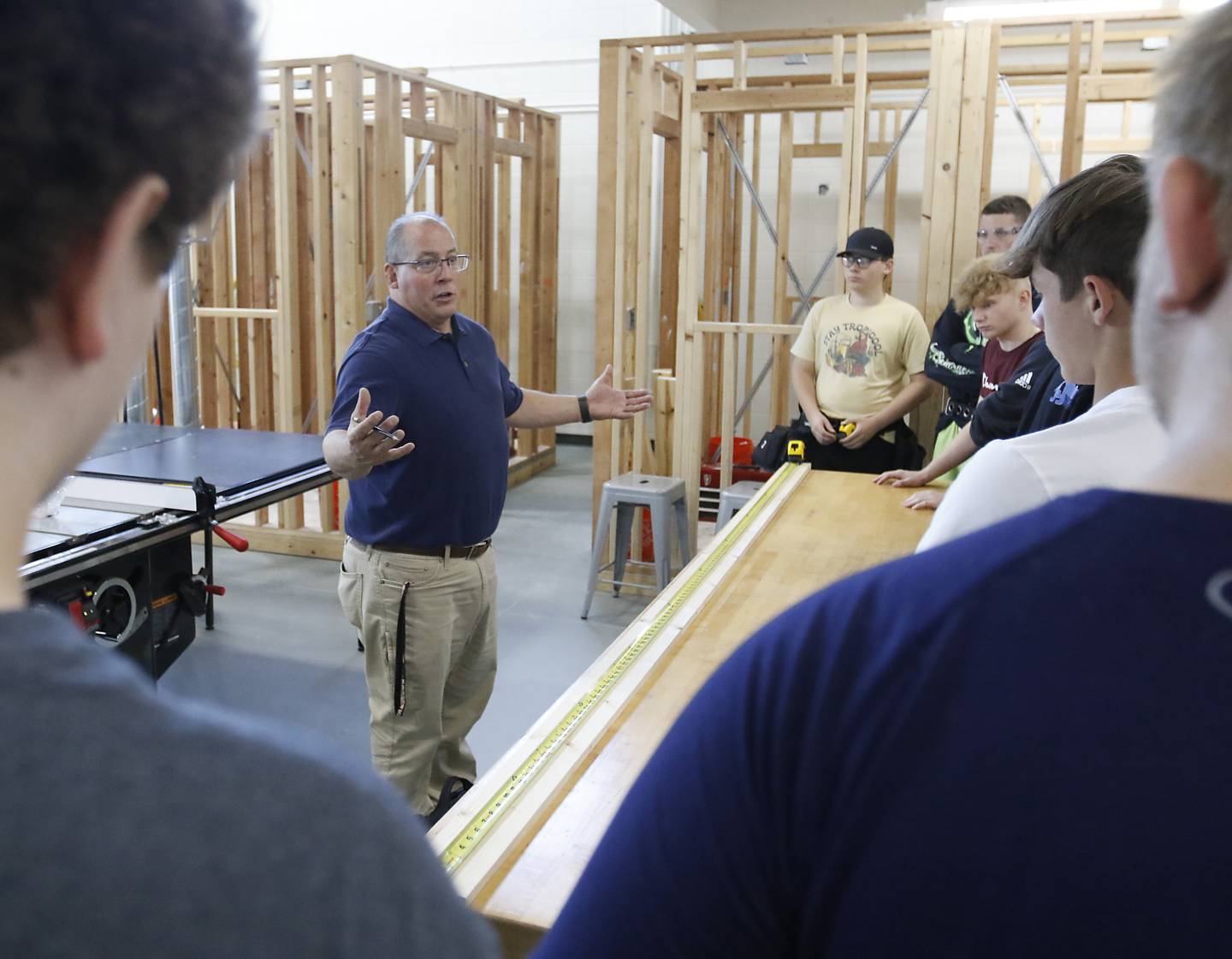 Dan Rohman teaches his construction trades students how to measure out a board to build a stud wall on Tuesday, Aug. 30, 2022, during class at McHenry High School. The students in the class will build the tiny shops that will house incubator retail businesses on McHenry's Riverwalk at Miller Point.