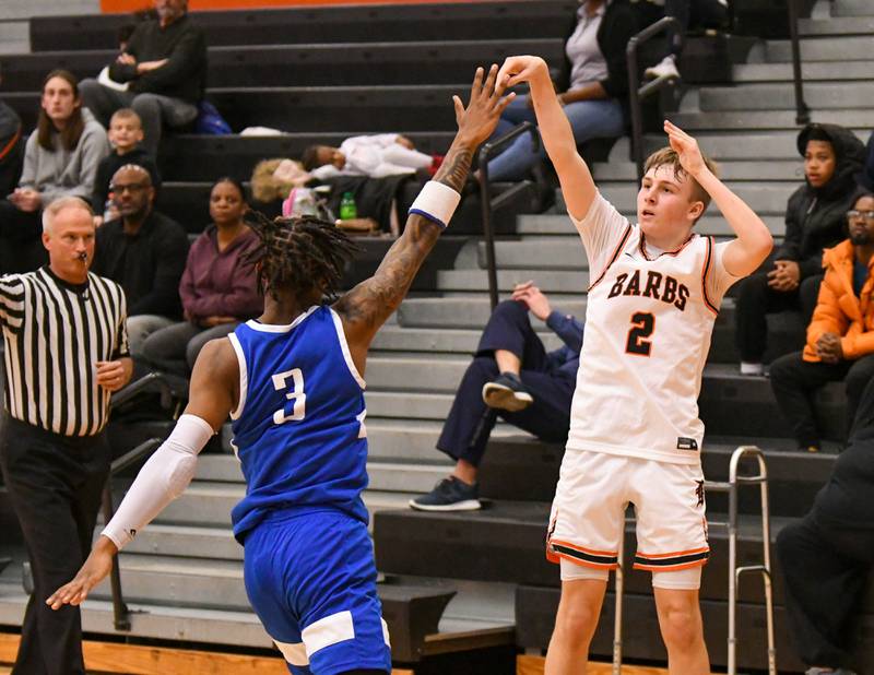 DeKalb Sean Reynolds (2) makes a three point basket while being defended by a Phillips player in the second quarter Friday Dec. 30th during The Chuck Dayton Classic Tournament held at DeKalb High School.