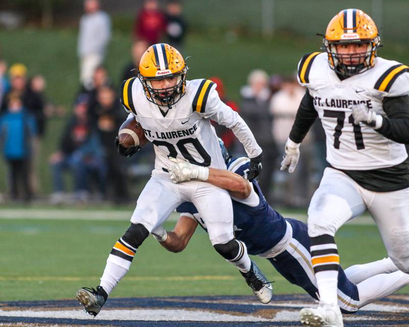 St Laurence's Harley Rizzs (20) runs through a tackle attempt by IC Catholic Prep's Nathen Omolo jr. (54) during Class 4A third round playoff football game between St Laurence at IC Catholic Prep.  Nov 11, 2023.