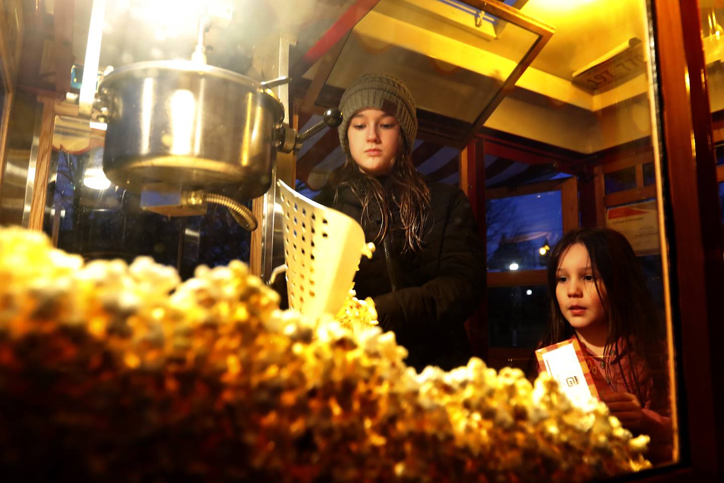Reese Uglinica, 10, and Avery Gonzalez, 5, get popcorn out of the 1928 Ford Model Popcorn Wagon operated by Reese’s father’s Scott Uglinica on Wednesday, Jan. 18, 2023, at Veterans Memorial Park in McHenry.