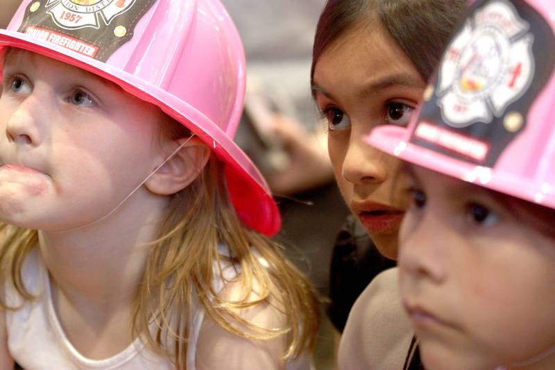 From left, Grace Kranz, 5, of Huntley, and sisters Myla Olivares, 7, and Chloe Olivares, 5, of Huntley, listen during story time as part of a Read & Eat Fries With a Firefighter event Thursday, March 16, 2023, at the Culver’s in Huntley.