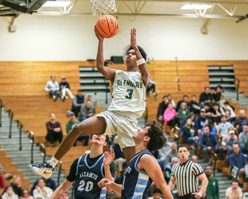 Glenbard West's TJ Williams (3) puts up an acrobatic shot during their Jack Tosh Holiday Classic basketball tournament game between Nazareth vs Glenbard West. Thursday Dec 26, 2024 in Elmhurst.