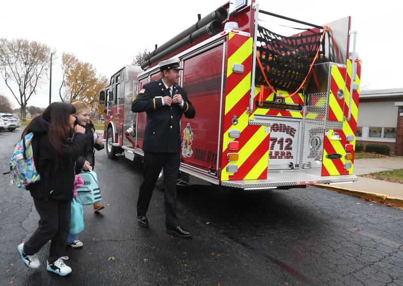 Putnam County Elementary students Priscilla Serna and Octavia Walter walk into school with Hennepin Fire Department lieutenant Tyler Smith on Tuesday, Nov. 21, 2023 at Putnam County Elementary School in Hennepin. The students won the Escape Floor Plan contest held by the fire depatment. Students had to draw a floor plan or map of their home showing all doors and windows. Smoke alarms had to be marked in each plan. A family meeting place was also required to be marked on the drawings. The Hennepin Fire Department has been holding the contest for several years. The department stopped the event during Covid and continued it for the first time since the pandemic this year. The department picks the winning children up on a firetruck and busses them to school.