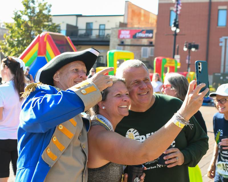 (From left) Justin Carlson, dressed as Baron Johann DeKalb, Emily Weller of DeKalb, and DeKalb Mayor Cohen Barnes pose for a photo during the Taste of DeKalb on Sunday, Sept. 29, 2024, held alongside the DeKalb Corn Classic 5K/10K races downtown.