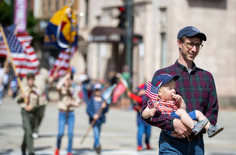 Andrew Nelms holds his son Teddy Nelms, 1, while they process with the American Heritage Girls Troop 224 in the St. Charles Memorial Day Parade in downtown St. Charles on Monday, May 26, 2025.