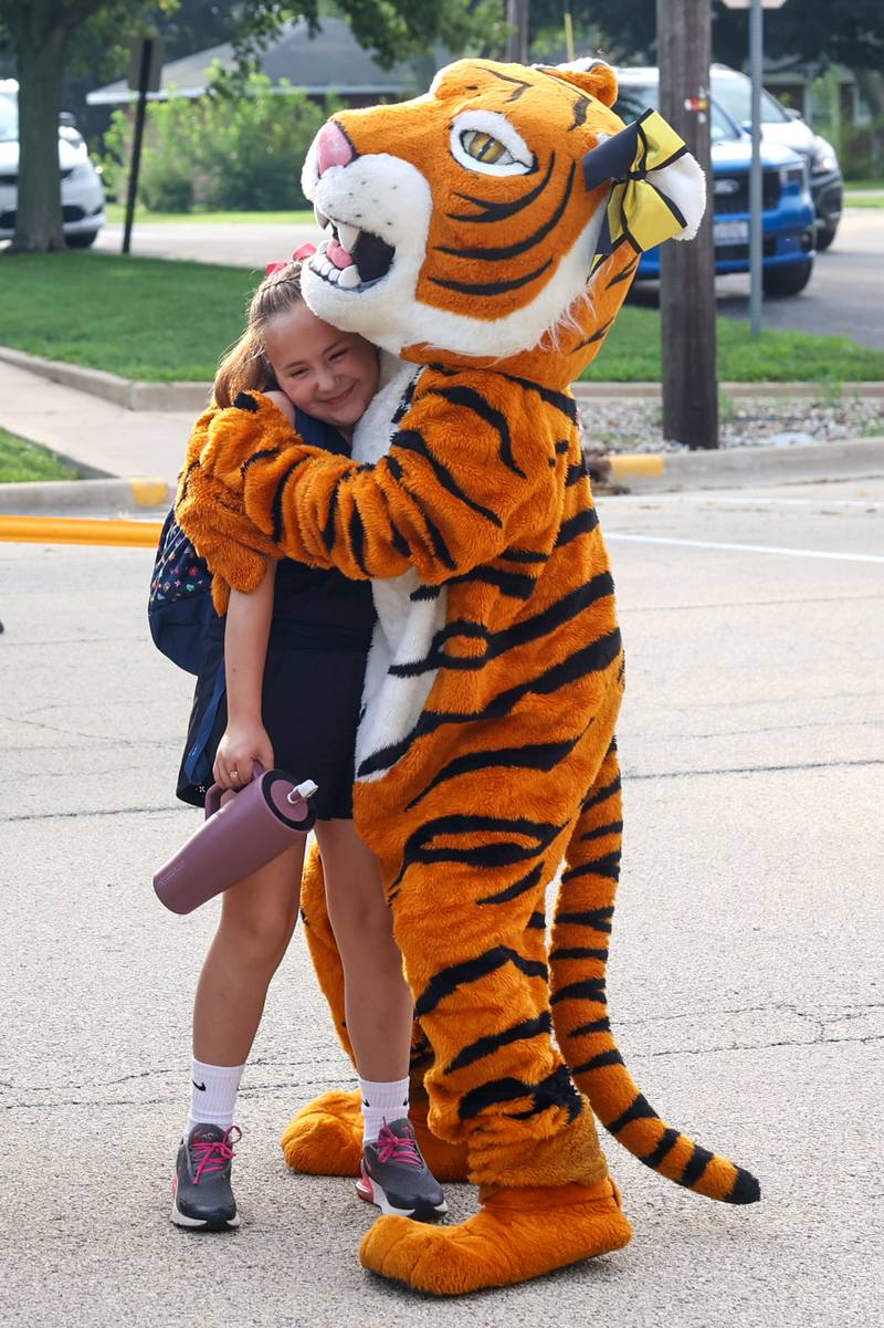 Herscher Intermediate School student Elany Quinones, right, receives a hug from the Tigers mascot as she arrives for her first day of fourth grade on Tuesday, Aug. 19, 2025.