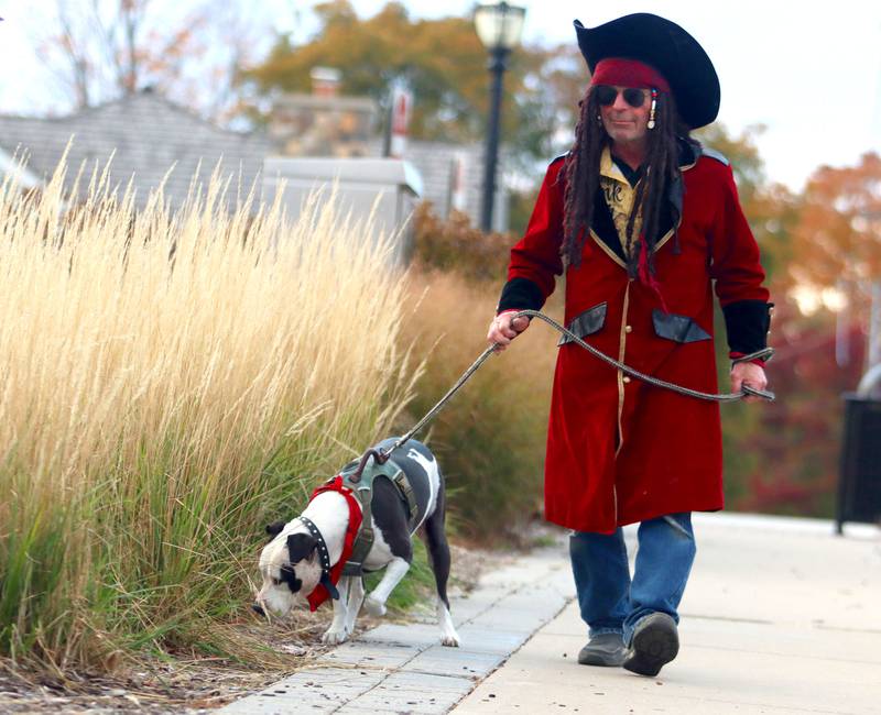 Jim Long of Crystal Lake, dressed as a pirate for Halloween, walks with his dog Annabelle in downtown Crystal Lake on Friday, October. 31, 2025
