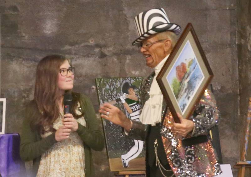 Aubrey Siebert a senior at St. Bede Academy, talks about her artwork with Don Grant Zellmer Madhatter host during the 7th annual Mad Hatter Ball on Friday, Nov. 17, 2023 at the Westclox Event Center in Peru.