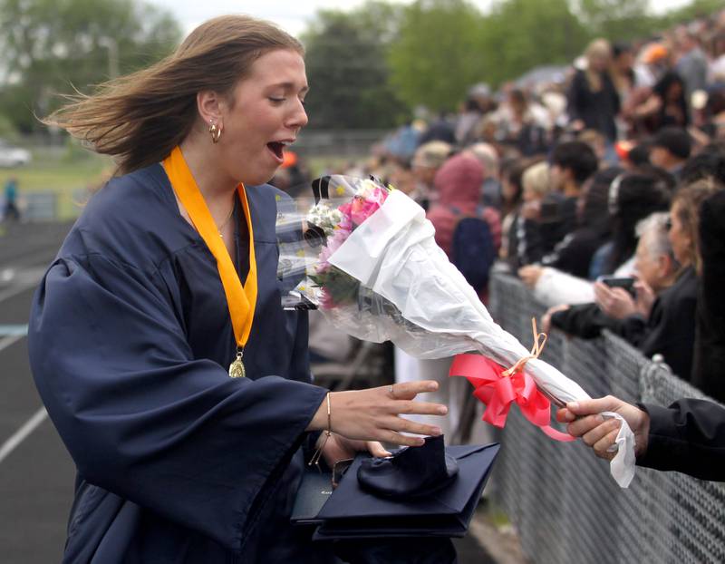 Elizabeth Mjaanes reacts as she receives flowers following graduation at Cary-Grove High School in Cary on Saturday, May 17, 2025.