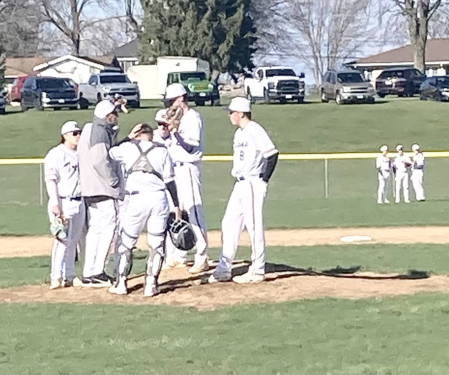 Mendota coach Jim Eustice makes a mound visit during Monday's game in Mendota with Hall as the Trojans outfielder have their own meeting of the minds..