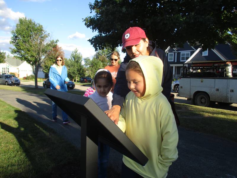 Circle Center first-grade student Jade Diaz, 6, reads a book page from the new Yorkville Storywalk on Sept. 27, 2022 in Yorkville Junior Women's Club Park as mother Angie Alaniz and sister Scarlett Diaz, 4, look on.