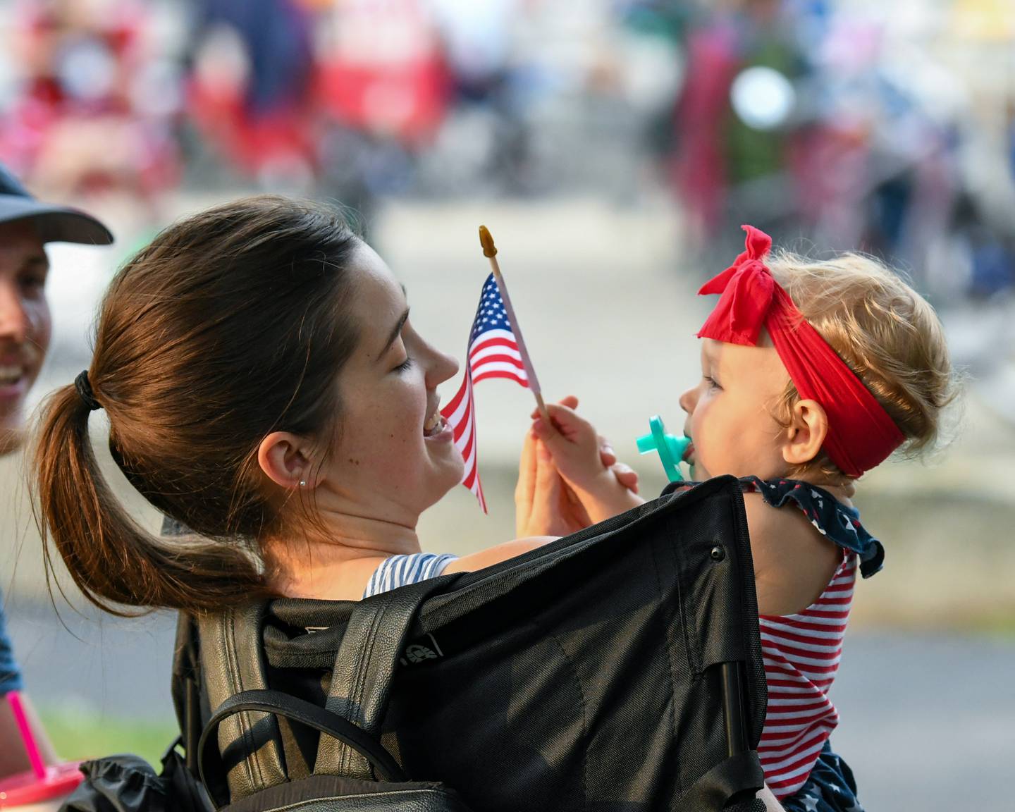 Haven Volz, 1, of DeKalb waves an American flag near her aunt Rachel Schad (left) of DeKalb as they wait for the fireworks show to start at Hopkins Park in DeKalb on Monday, July 4, 2022.