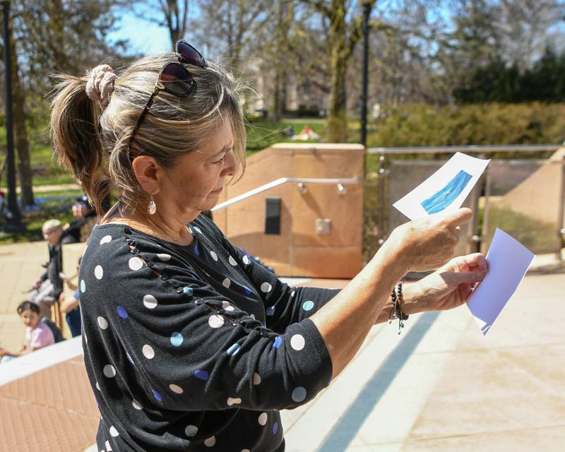 As the solar eclipse was starting Christine Morris of Wheaton tries out her pinhole solar eclipse viewer she made through the Wheaton library on Monday April 8, 2024.