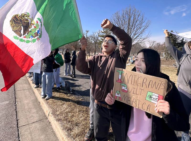 DeKalb High School senior Kevin Mejia, (left) 18, and junior Ailany Padilla, 17, cheer as passing motorist honk in support Tuesday, Feb. 10, 2026, during the groups protest on Sycamore Road in front of Hopkins Park in DeKalb. The students walked out of school Tuesday to protest against ICE involved violence and arrests.