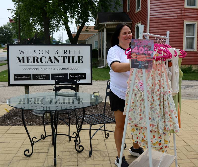 Brittany Sabatino, of Wilson Street Mercantile, sets up a sales rack on the sidewalk for Boo Boo Days in Batavia on Sunday, July 13, 2025.