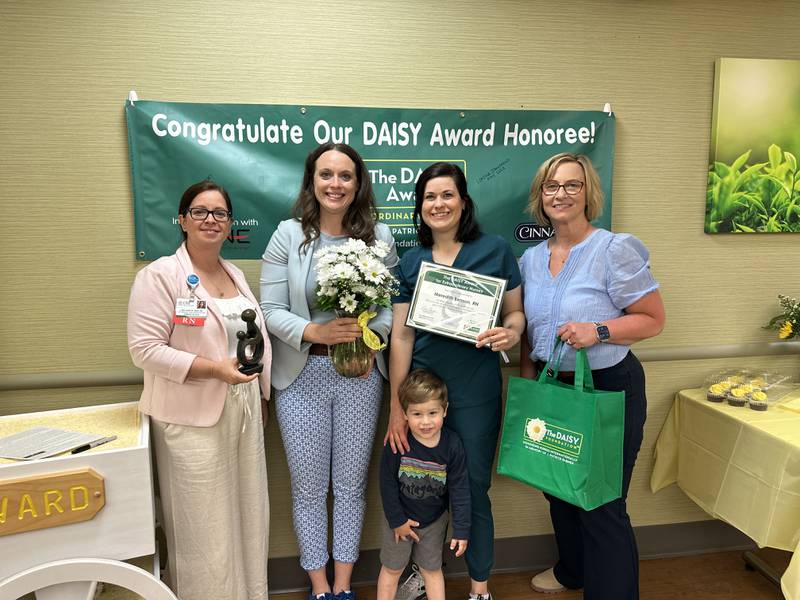 Lisa Garcia, chief nursing officer; Lori Anderson, Emergency Department manager, Meredith Benson, BSN, RN, (pictured with her son); and Jackie Kernan, president; take a photograph together after Benson was named OSF Saint Clare's 2024 DAISY Award winner.