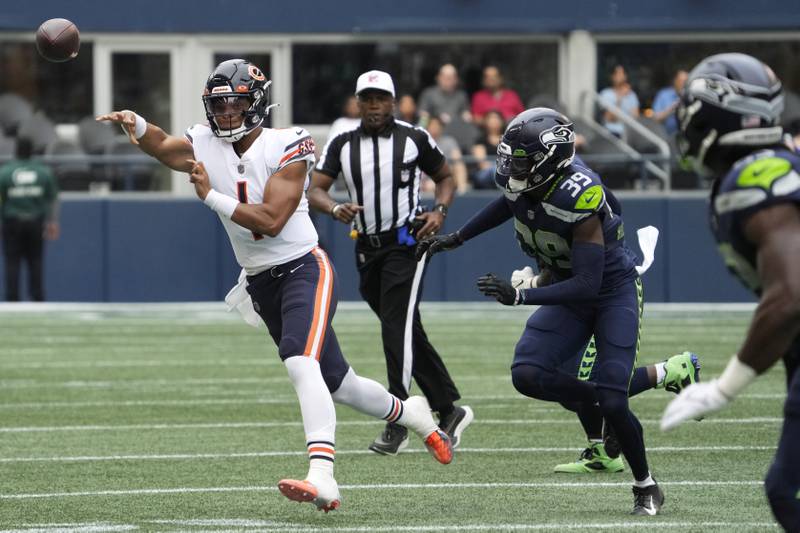 Chicago Bears quarterback Justin Fields passes under pressure from Seattle Seahawks cornerback Tariq Woolen during the first half, Thursday, Aug. 18, 2022, in Seattle.