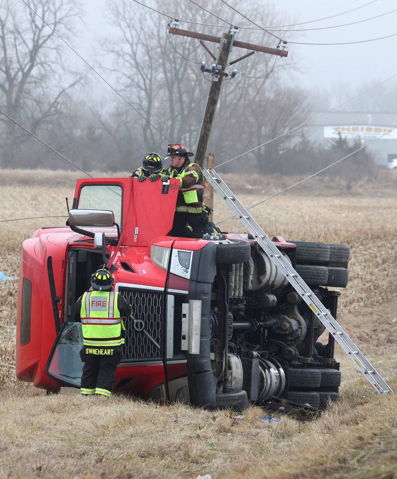 Firefighters work to secure the cab of a semitrailer that rolled into the ditch Wednesday, Jan. 7, 2026, on the north side of Lincoln Highway in Cortland.
