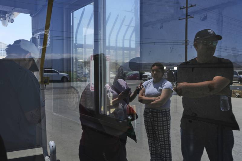 FILE - People wait outside of Glass House Farms, a day after an immigration raid on the facility, Friday, July 11, 2025, in Camarillo, Calif. (AP Photo/Jae C. Hong, File)