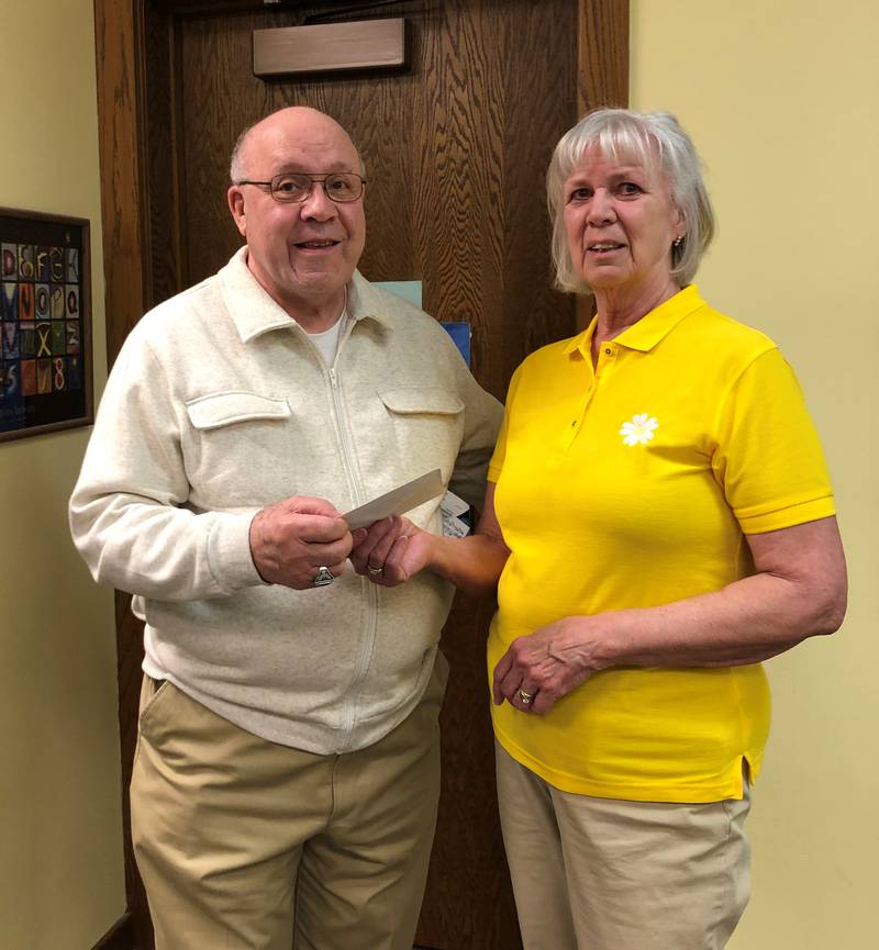PEO Chapter DX president Elli McLaughlin (right) giving donation check of $125 to John Rey of the DeKalb/Sycamore Bookcase Project. Photo provided by Linda Sherman.