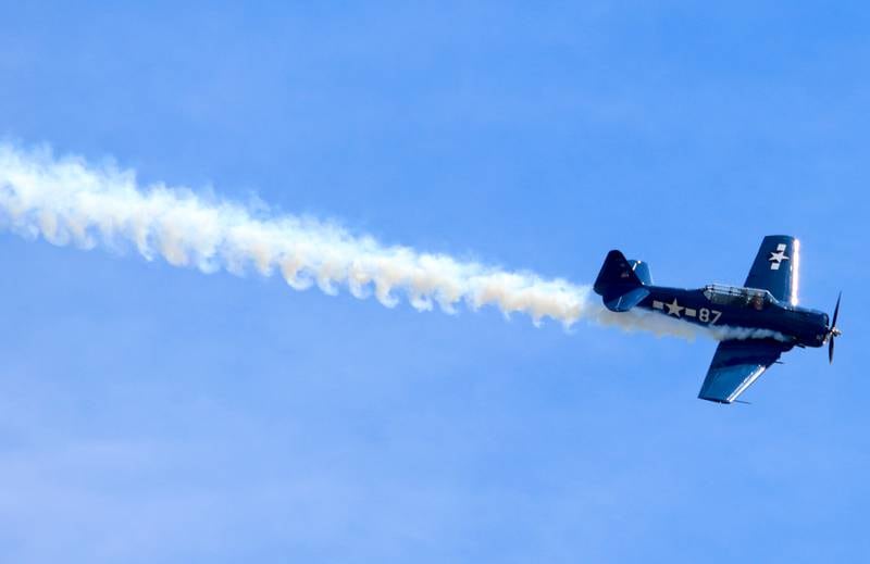 A vintage plane streams above during a Memorial Day service and parade in downtown Woodstock on Monday, May 26, 2025.