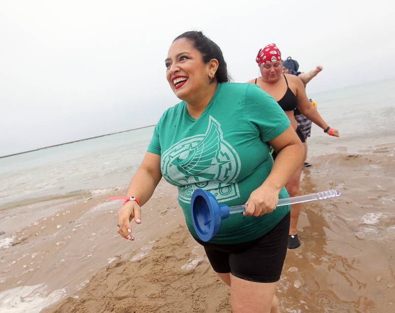 JoAnn Flores-Deter, of Waukegan holds a plunger Jan. 1 while coming out of the cold water after taking the plunge in Lake Michigan during the 24th annual Waukegan Polar Bear Plunge at Waukegan Municipal Beach. Genevive Klimala, of Burlington, Wis., followed behind her.