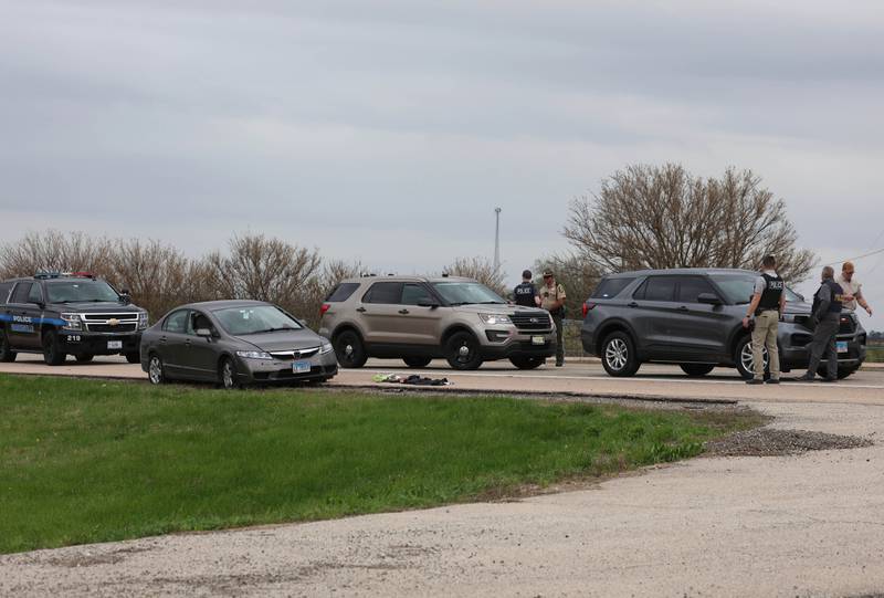 Law enforcement officials gather around a Honda sedan with a shattered window Monday, April 27, 2026, during an investigation on Interstate 88 just west of Keslinger Road in Maple Park.