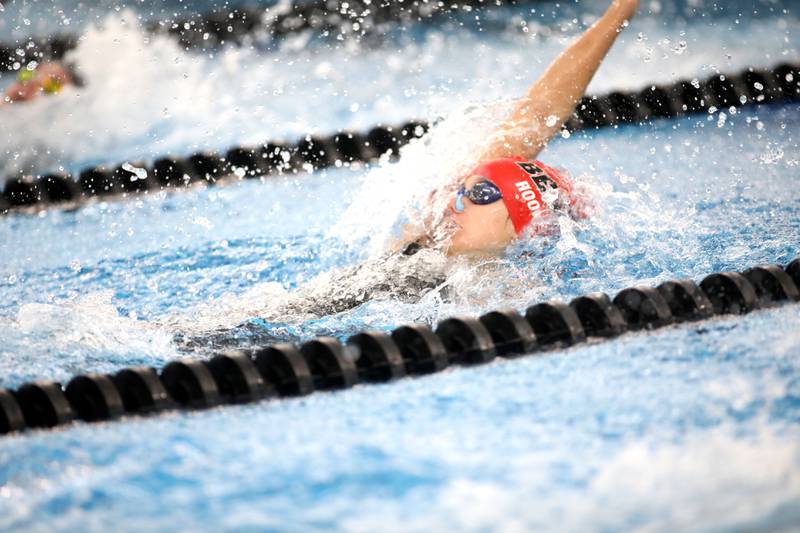 Benet’s Lucy Rooney competes in the 100-yard backstroke consolation heat during the IHSA Girls State Championships on Saturday, Nov. 16, 2024 at FMC Natatorium in Westmont.