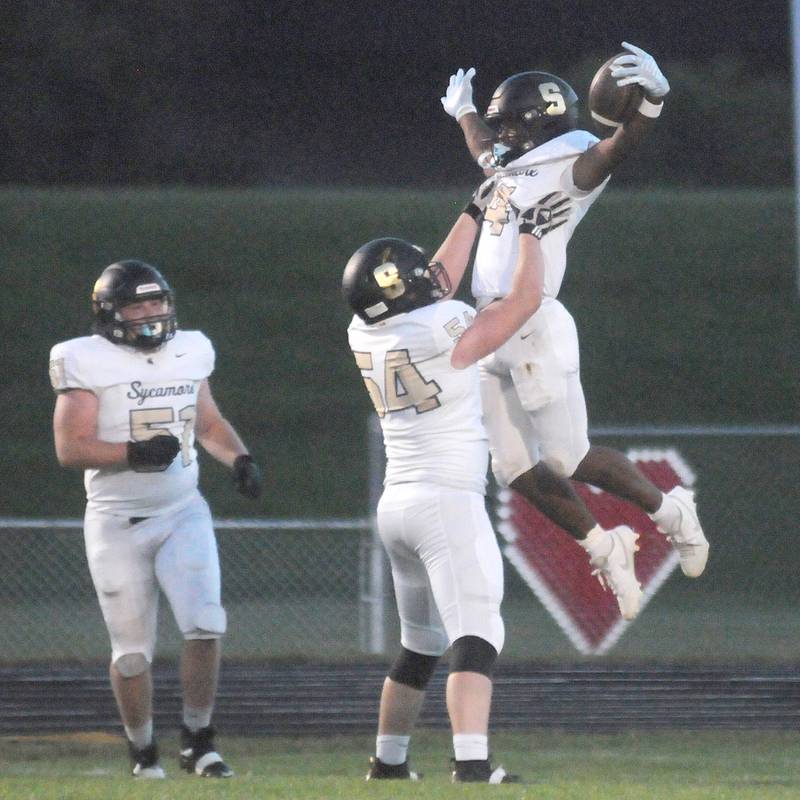 Sycamore teammates Gable Carrick (51), Tristan Countryman (54) and Tyler Curtis celebrate Curtis' first touchdown of the night against Ottawa  at King Field on Friday, Sept. 15, 2023.