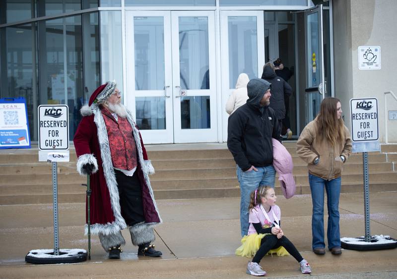 Santa Claus waits with other spectators for runners to cross the finish line in the 35th annual Jingle Bell Run at Kankakee Community College on Sunday, December 7, 2025.