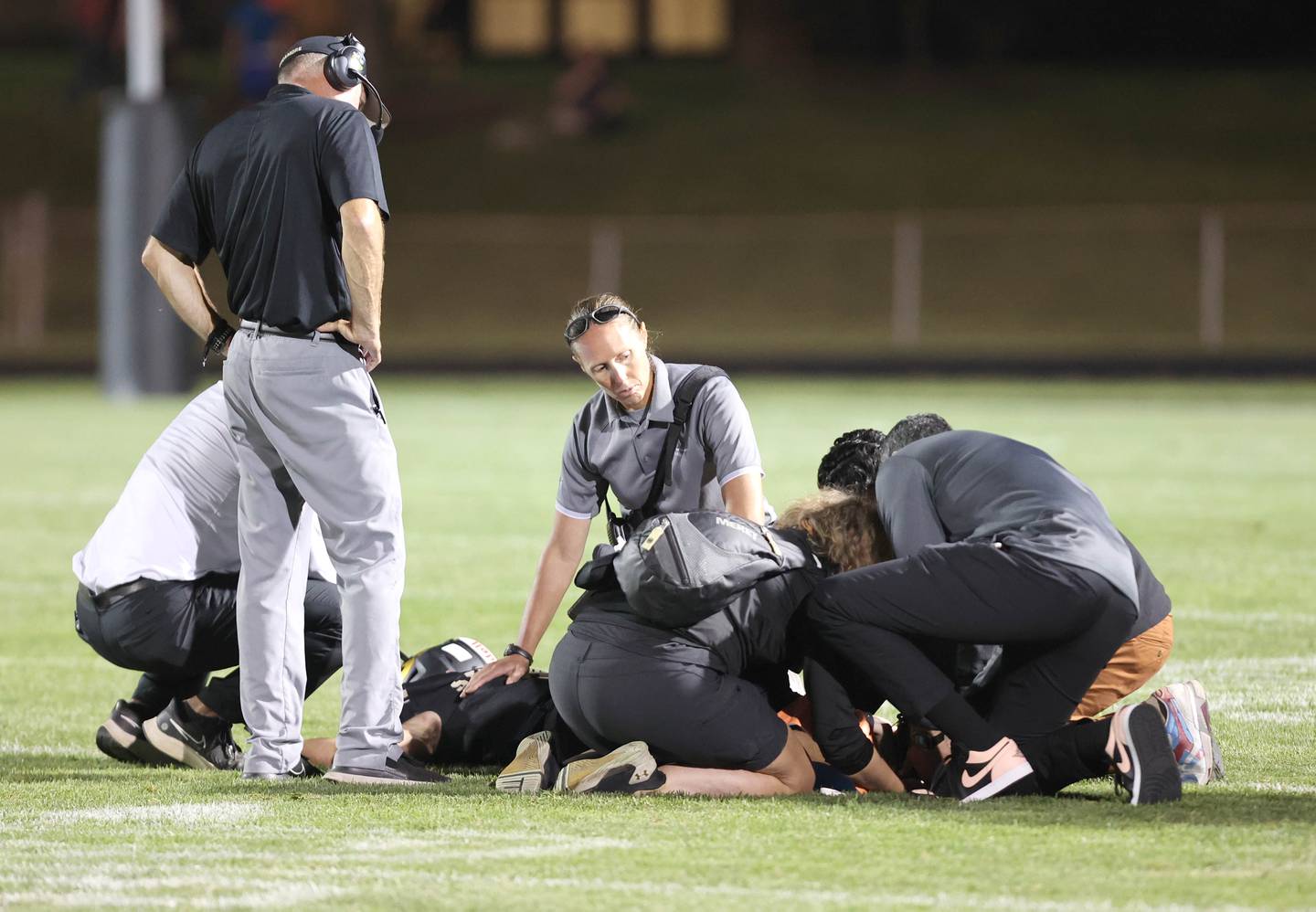 Shelby Bernard, (middle) an athletic trainer with Northwestern Medicine, and Ankur Rishi Behl, (right) an orthopedic surgeon with Northwestern Medicine, along with Sycamore coaches and members of the Sycamore High School athletic training staff treat an injured player during the football game Friday Sept.  2, 2022, at Sycamore High School.